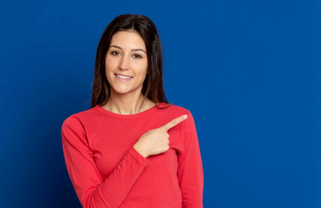 Mulher vestida com camiseta vermelha de manga indicando os 10 itens que valorizamos no trabalho